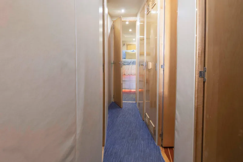 Slide: The Image of Hallway inside 1999 Bertram 60 Convertible yacht with wooden doors and blue carpet. - 36