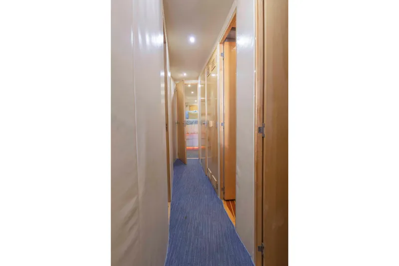 Slide: The Image of Interior hallway of a 1999 Bertram 60 Convertible yacht with wooden doors and blue carpet. - 37