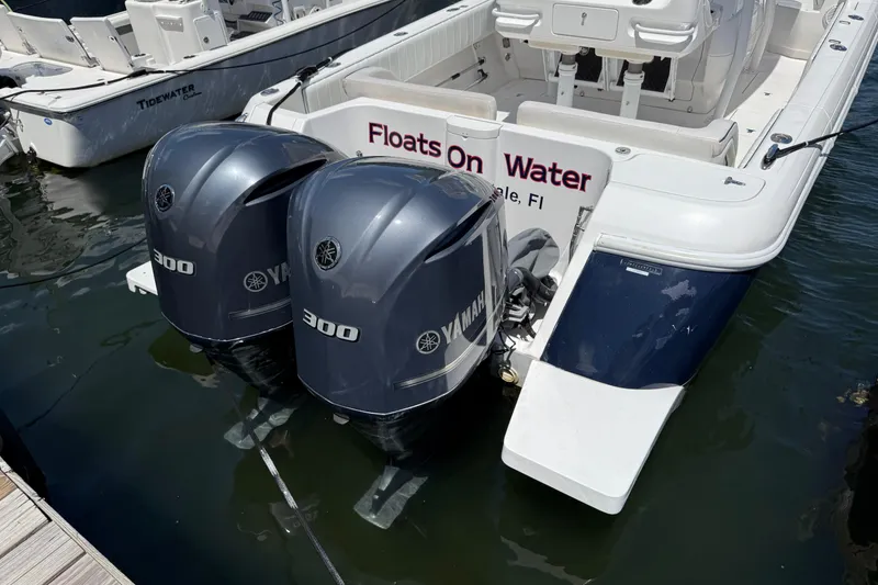 The Image of 2013 Intrepid 327 Cuddy boat with twin Yamaha 300 engines docked in water. - 0