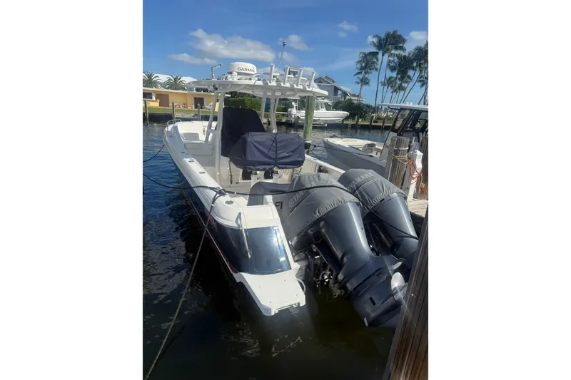 The Image of 2013 Intrepid 327 Cuddy boat docked with twin Yamaha engines, under clear blue sky. - 1