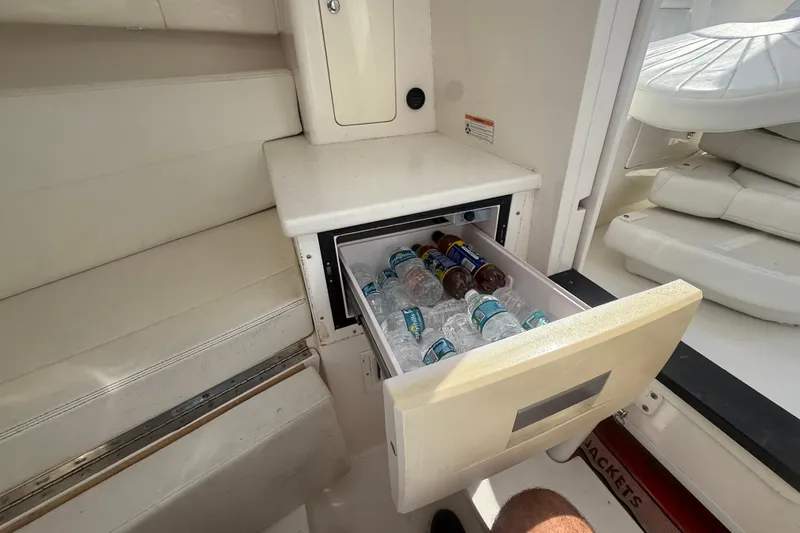 Slide: The Image of 2013 Intrepid 327 Cuddy boat interior with open cooler drawer containing drinks. - 22