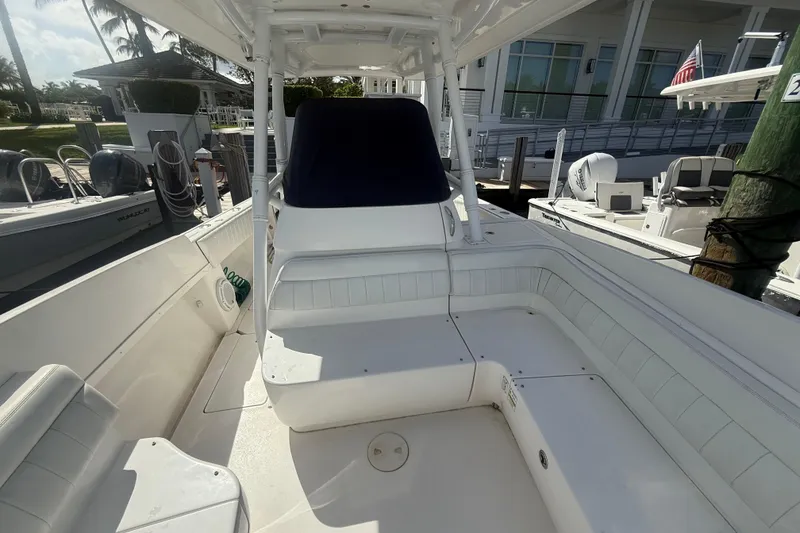 Slide: The Image of 2013 Intrepid 327 Cuddy boat interior with white seating and docked at marina. - 8