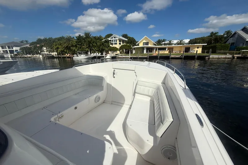 Slide: The Image of 2013 Intrepid 327 Cuddy boat interior with white seating, docked by waterfront homes. - 9