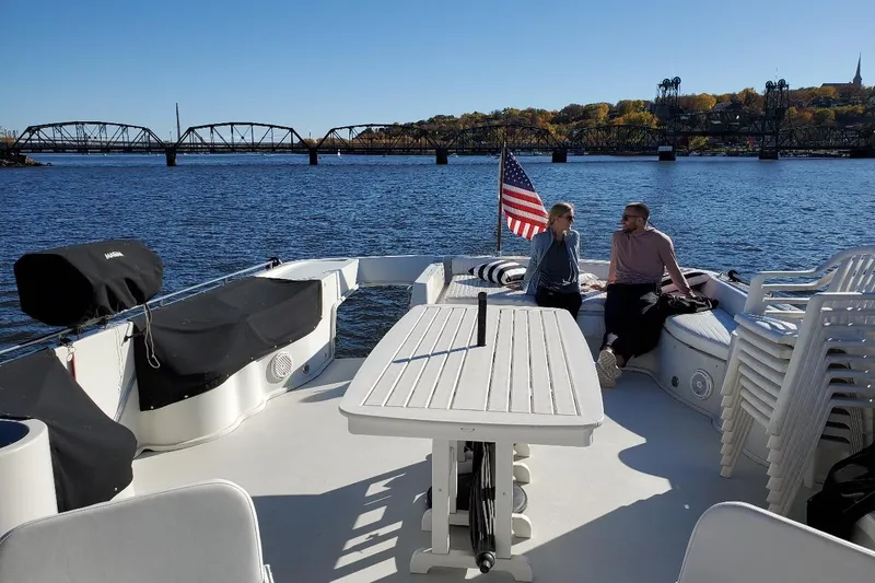 Slide: The Image of Two people relaxing on a 1992 Bluewater 54 Coastal Cruiser, with scenic river view. - 12