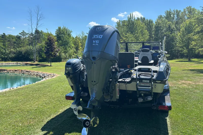 Slide: The Image of 2025 Skeeter WXR2260 boat with powerful outboard motors, parked on grassy area near a pond. - 7