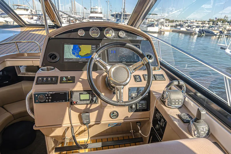 Slide: The Image of Helm of 2016 Regal 46 Sport Coupe with navigation screens and controls, docked at marina. - 17
