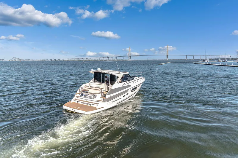Slide: The Image of 2016 Regal 46 Sport Coupe cruising on open water under a clear blue sky. - 49