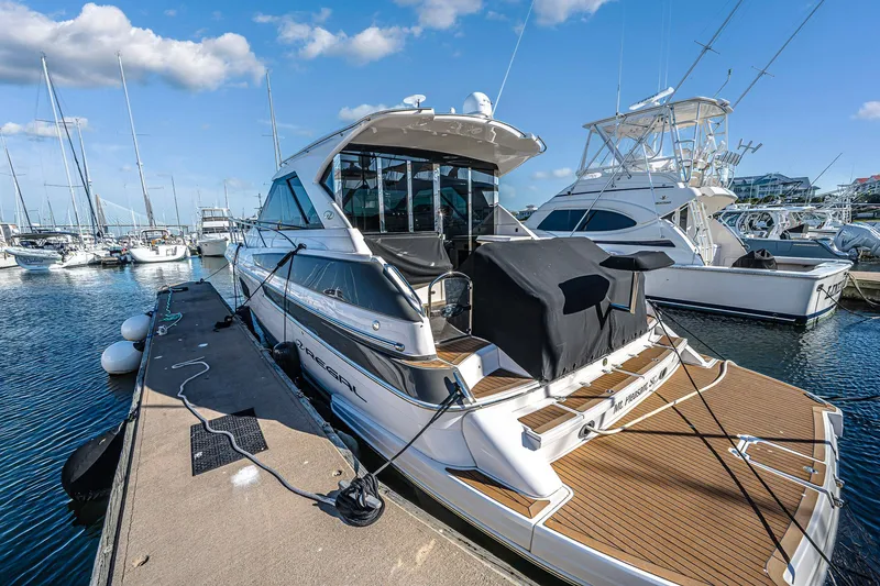 Slide: The Image of 2016 Regal 46 Sport Coupe yacht docked at marina under blue sky. - 53