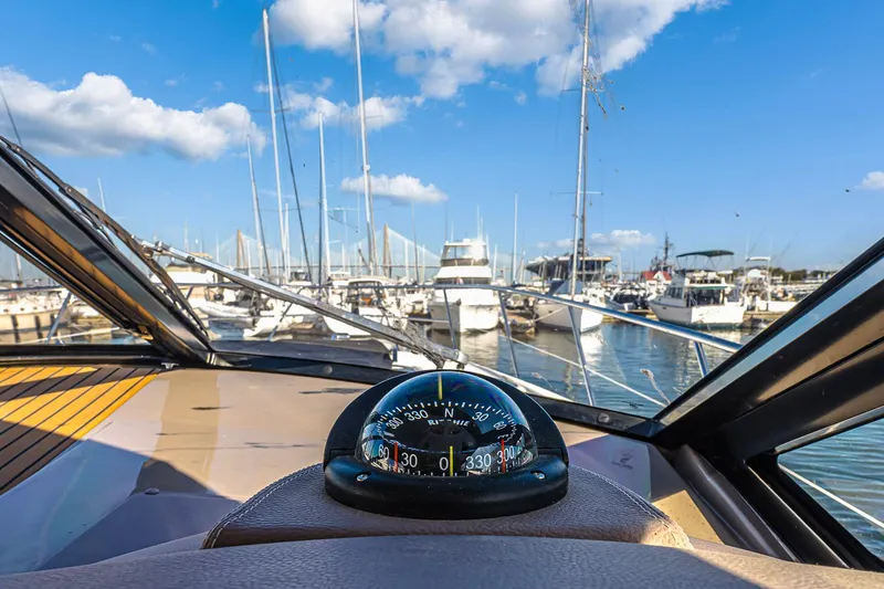 Slide: The Image of 2016 Regal 46 Sport Coupe cockpit view with compass, marina background. - 57