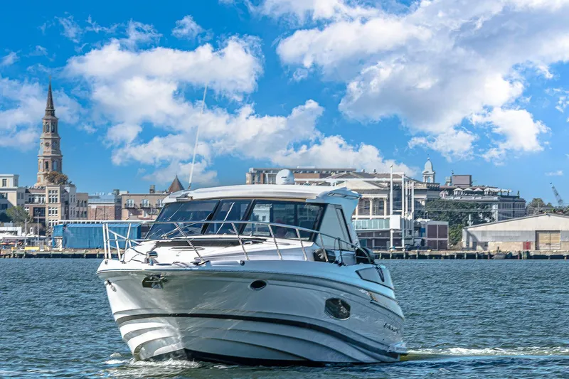 Slide: The Image of 2016 Regal 46 Sport Coupe yacht cruising near a city waterfront under blue skies. - 77