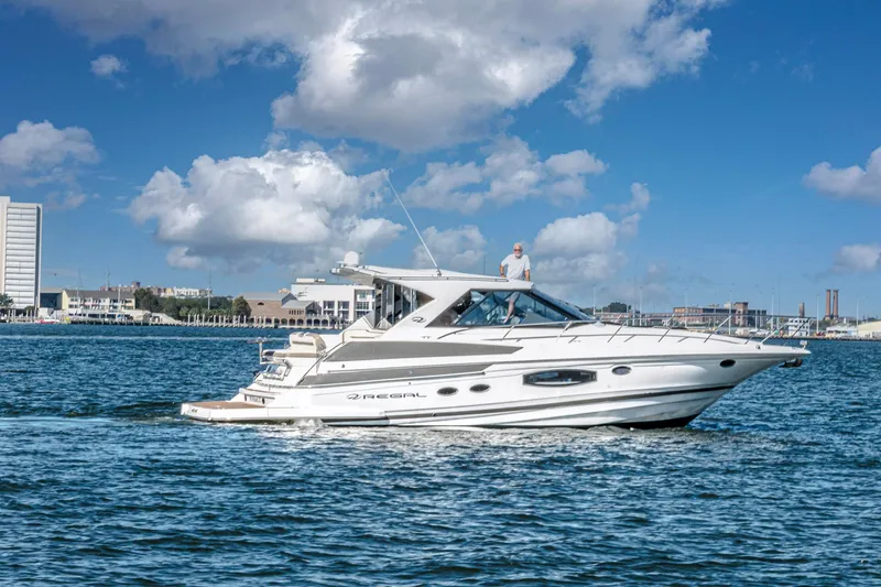 Slide: The Image of 2016 Regal 46 Sport Coupe yacht cruising on a sunny day with cityscape background. - 82