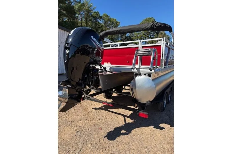 Slide: The Image of 2026 Sun Tracker Party Barge 22 RF DLX with Mercury outboard motor, parked on trailer. - 2