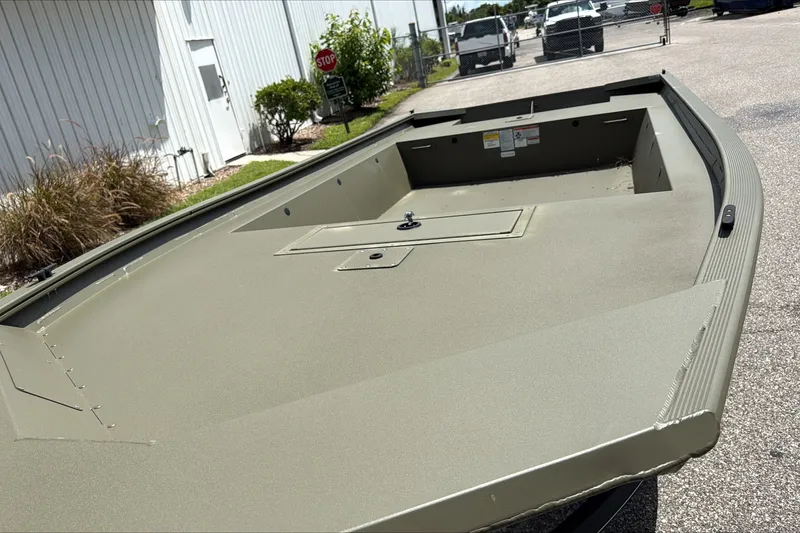 The Image of 2026 Tracker Grizzly 1754 Utility boat, olive green, parked outdoors near a building. - 0