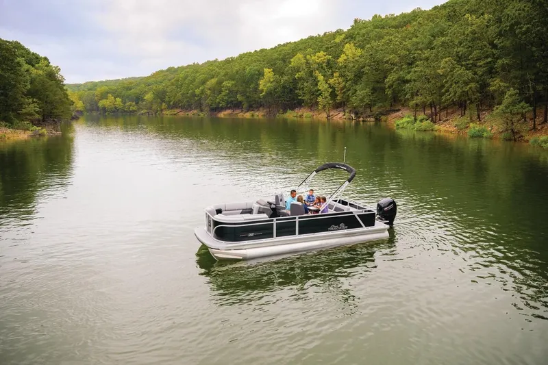 Slide: The Image of 2026 Sun Tracker Party Barge 22 RF DLX on a serene lake surrounded by lush trees. - 12