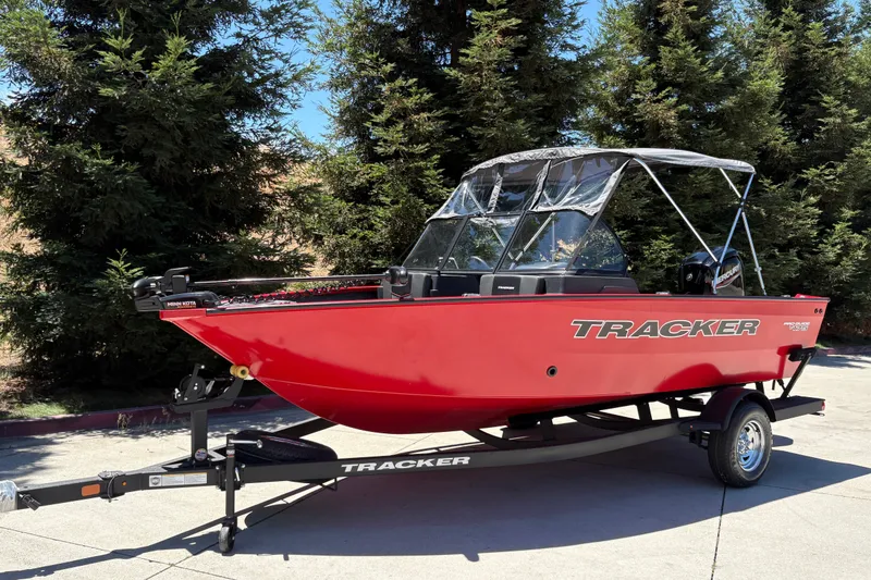 Slide: The Image of 2026 Tracker Pro Guide V-175 WT boat in vibrant red on a trailer, surrounded by trees. - 8