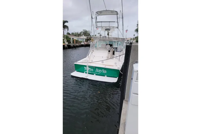 Slide: The Image of 2004 Cabo 40 Express boat docked, rear view with green nameplate "Miss Jayla." - 1