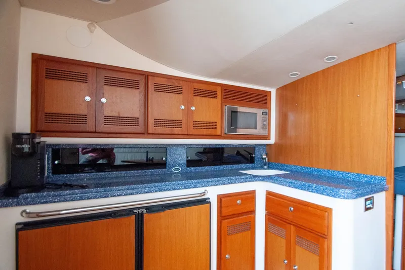 Slide: The Image of 2004 Cabo 40 Express yacht kitchen with wooden cabinets, blue countertops, and built-in microwave. - 17