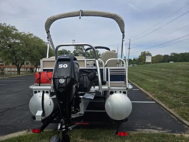 Slide: The Image of 2025 Sun Tracker Bass Buggy 16 XL Select pontoon boat with 50 HP engine in parking lot. - 3