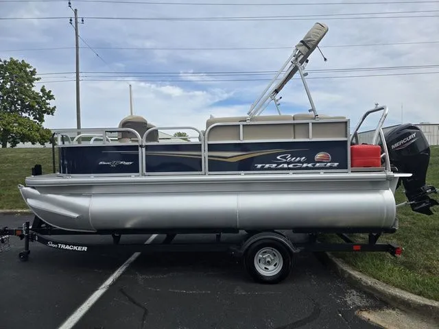 Slide: The Image of 2025 Sun Tracker Bass Buggy 16 XL Select pontoon boat on trailer, parked outdoors. - 5