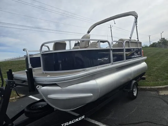 Slide: The Image of 2025 Sun Tracker Bass Buggy 16 XL Select pontoon boat on trailer, parked outdoors. - 6