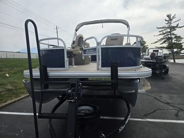 Slide: The Image of 2025 Sun Tracker Bass Buggy 16 XL Select pontoon boat on trailer, parked outdoors. - 7