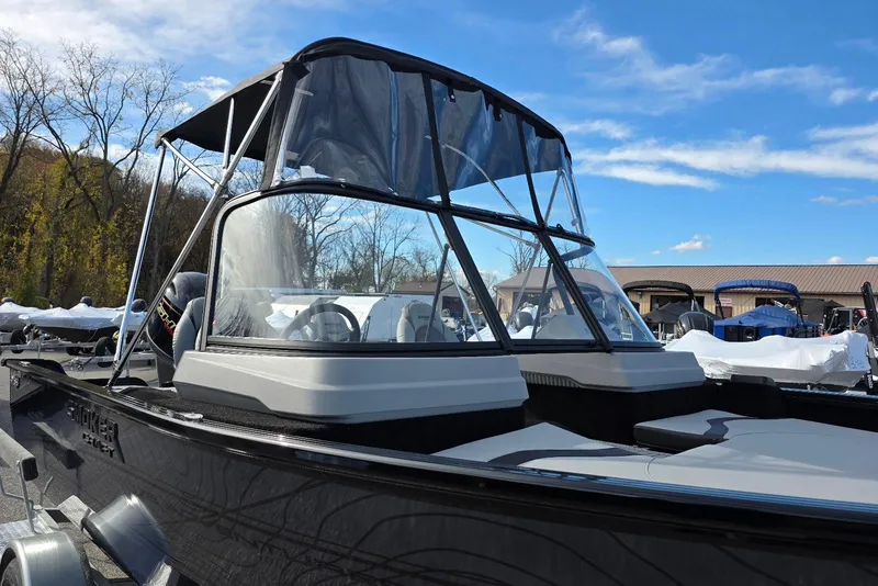 Slide: The Image of 2026 Smoker Craft Adventurer 178 DC boat with canopy, parked outdoors under blue sky. - 6