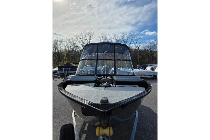 Slide: The Image of 2026 Smoker Craft Adventurer 178 DC boat, front view, parked outdoors under a cloudy sky. - 8