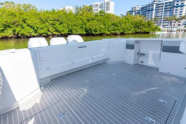 Slide: The Image of 2023 Intrepid 438 Evolution boat deck with sleek design, surrounded by lush greenery. - 13