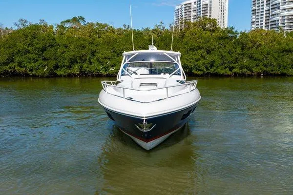 Slide: The Image of 2023 Intrepid 438 Evolution yacht on calm water, surrounded by greenery and cityscape. - 2