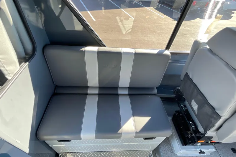 Slide: The Image of 2026 Hewescraft 250 Alaskan ET HT interior seating with gray upholstery and window view. - 17