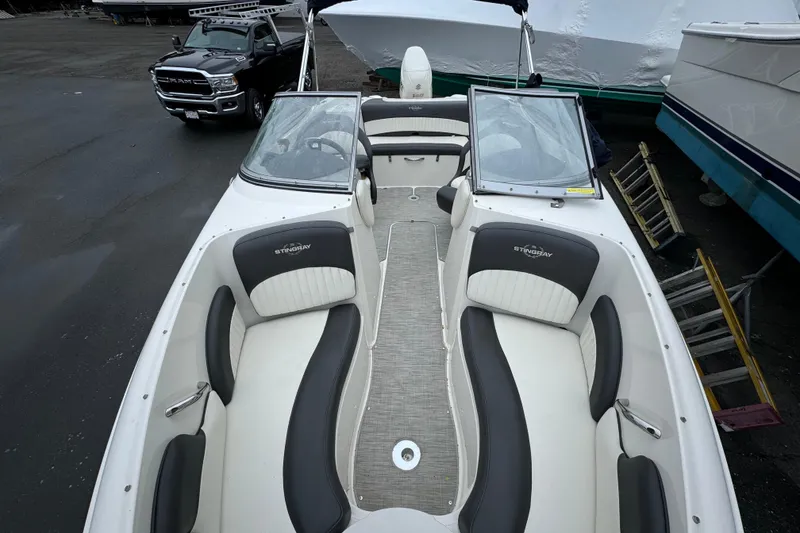 Slide: The Image of 2017 Stingray 204 LR boat interior with seating, parked near a truck. - 6