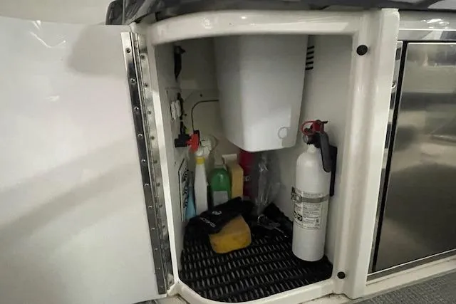 Slide: The Image of 2017 Formula 350 Crossover Bowrider storage compartment with cleaning supplies and fire extinguisher. - 59