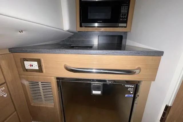 Slide: The Image of 2017 Formula 350 Crossover Bowrider interior kitchen with microwave and fridge. - 67