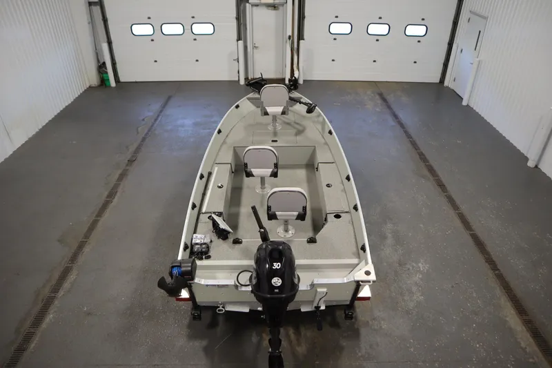Slide: The Image of 2024 Starcraft Patriot 14 TL boat in a garage, rear view with motor and seating. - 10