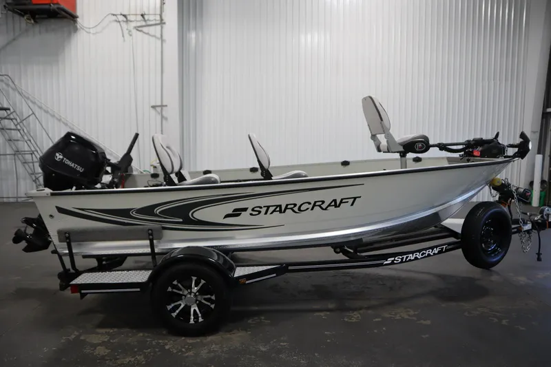 Slide: The Image of 2024 Starcraft Patriot 14 TL boat with Tohatsu motor on trailer in garage. - 4