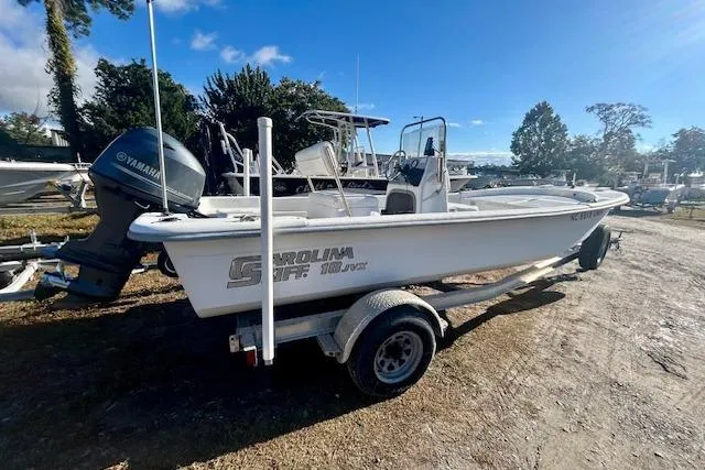 Slide: The Image of 2009 Carolina Skiff JVX18CC boat on trailer, parked outdoors under clear sky. - 2
