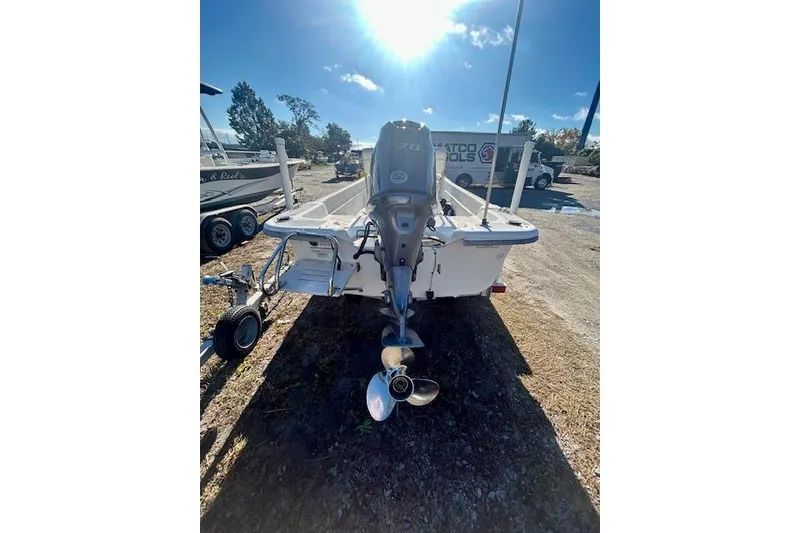 Slide: The Image of 2009 Carolina Skiff JVX18CC boat with outboard motor, parked on a trailer under sunny skies. - 8