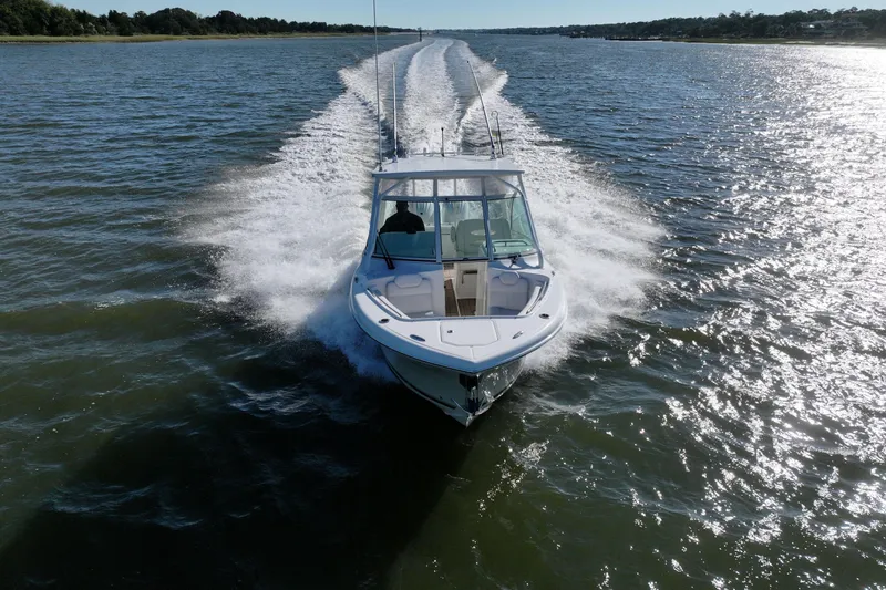 Slide: The Image of 2022 Albemarle 27 DC boat cruising on open water, creating a wake. - 11