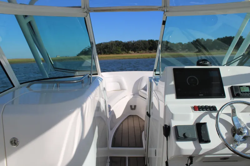 Slide: The Image of 2022 Albemarle 27 DC boat interior with steering console and seating, on a sunny day. - 33