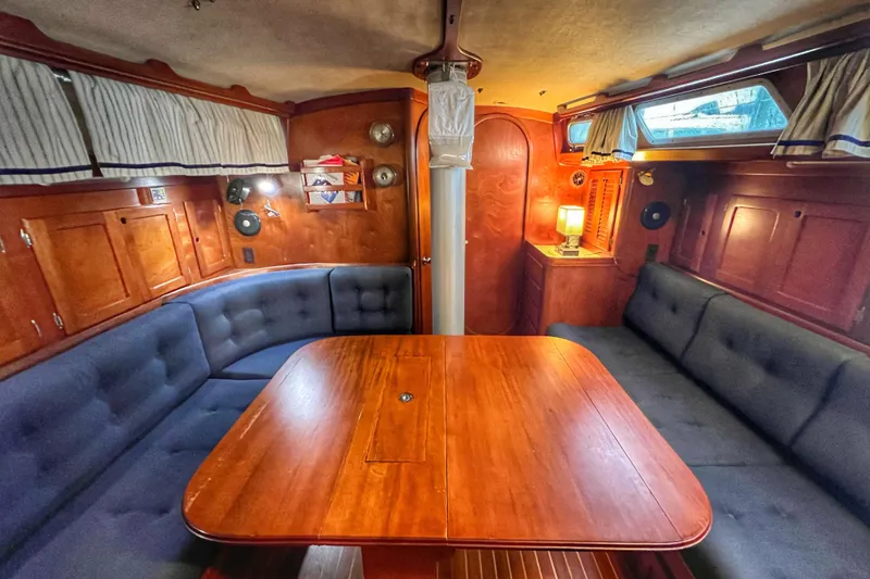 Slide: The Image of Interior of 1987 Bristol 41.1 Aft Cockpit sailboat with wooden table and cushioned seating. - 10