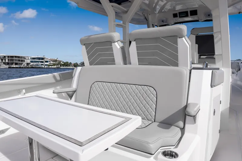 Slide: The Image of 2022 Pursuit S 428 Sport boat interior with sleek seating and table, dockside view. - 14