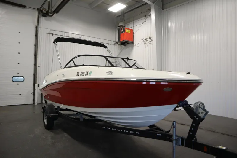 Slide: The Image of 2021 Bayliner VR5 Bowrider OB in a garage, red and white exterior, on a trailer. - 3