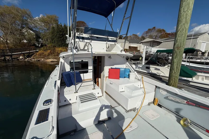 Slide: The Image of 1963 Bertram 31 Flybridge Cruiser docked, featuring spacious deck and colorful cushions. - 10