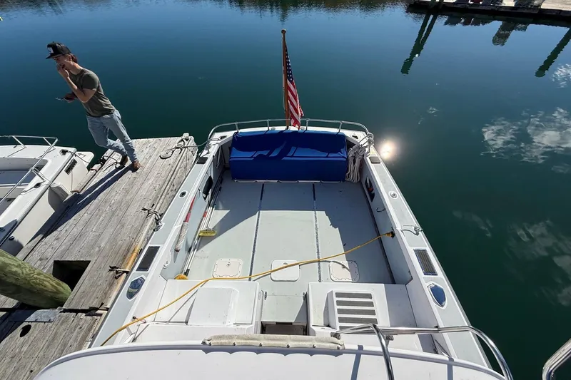 Slide: The Image of 1963 Bertram 31 Flybridge Cruiser docked, with American flag and person on pier. - 12