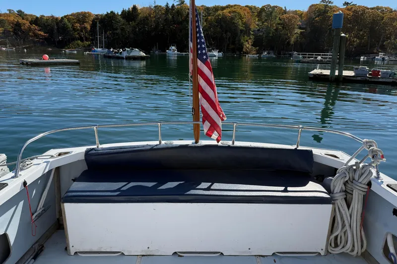 Slide: The Image of 1963 Bertram 31 Flybridge Cruiser with American flag, docked in scenic marina. - 13