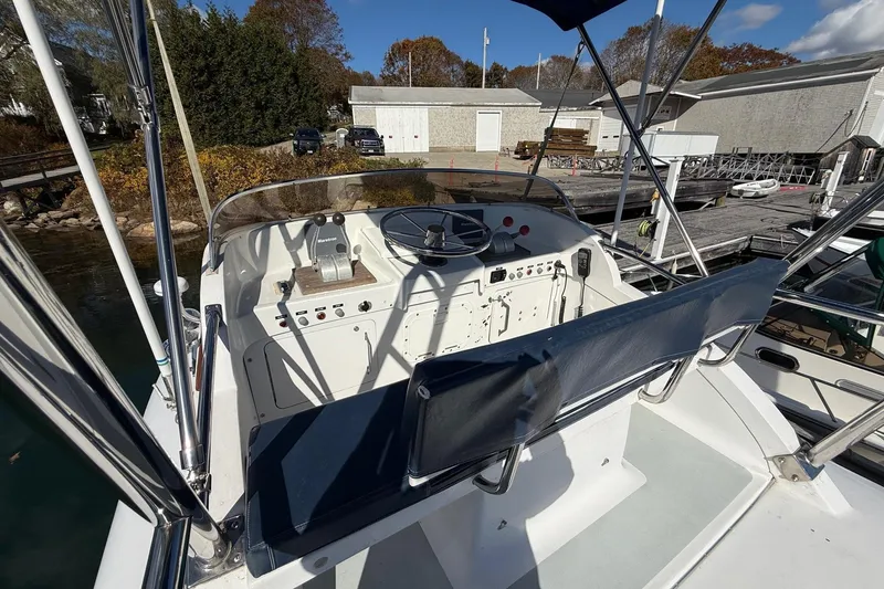 Slide: The Image of 1963 Bertram 31 Flybridge Cruiser helm with controls and seating, docked at a marina. - 18