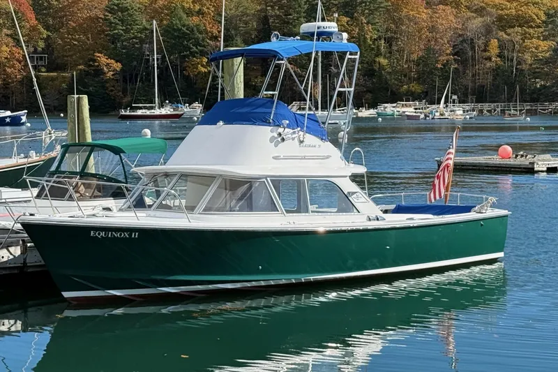 Slide: The Image of 1963 Bertram 31 Flybridge Cruiser docked in a scenic marina setting. - 2