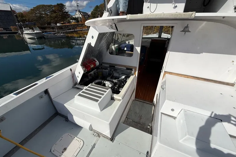 Slide: The Image of 1963 Bertram 31 Flybridge Cruiser with open engine compartment, docked by calm waters. - 26