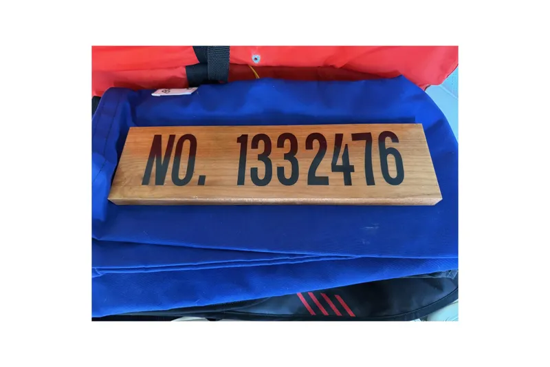 Slide: The Image of Wooden plaque with "NO. 1332476" on blue fabric, related to 1963 Bertram 31 Flybridge Cruiser. - 48