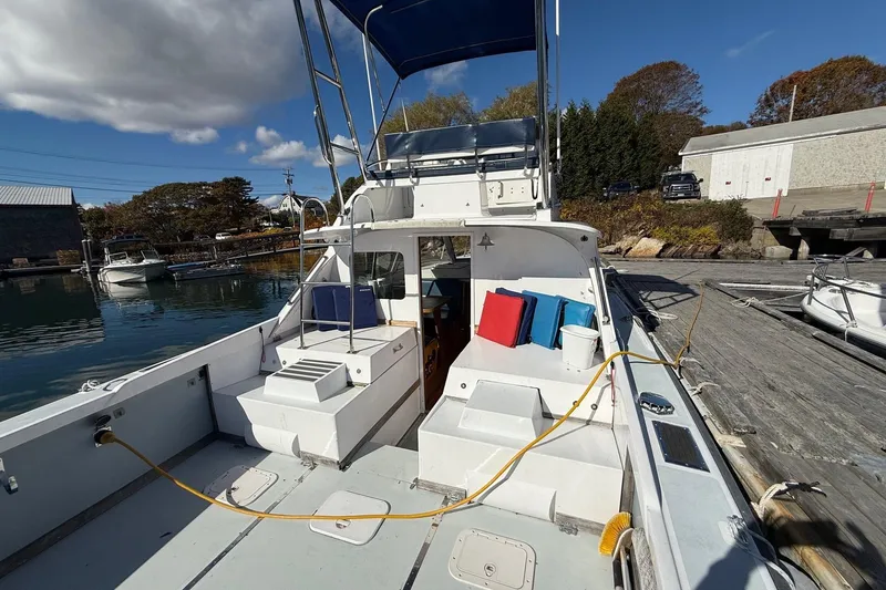 Slide: The Image of 1963 Bertram 31 Flybridge Cruiser docked, featuring spacious deck and vibrant cushions. - 9
